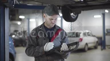 自信严肃的白人男子的肖像，看着车底，并注意到电脑。 专业维修